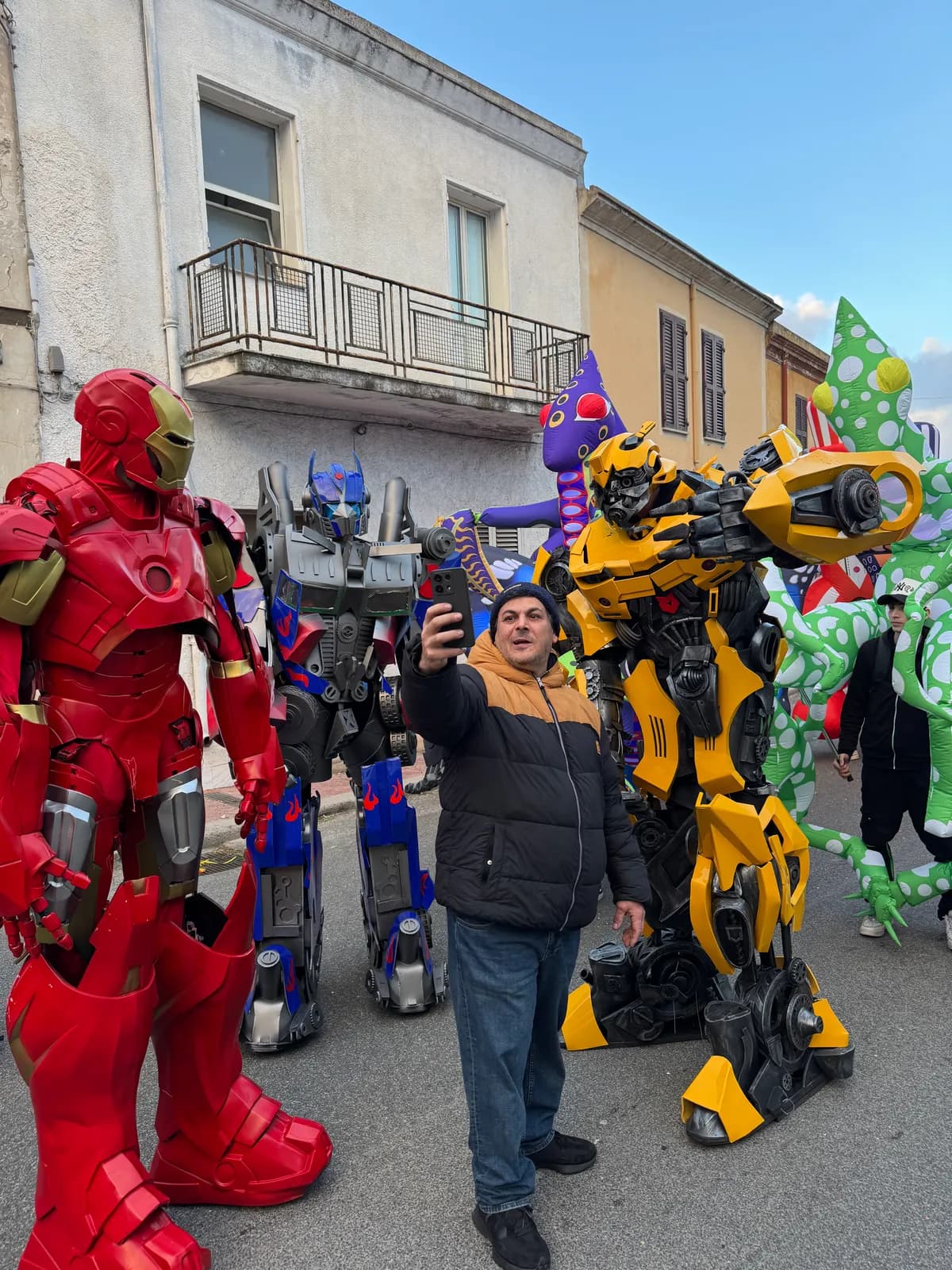 Le mascotte giganti dei Transformers e Iron Man in piazza, mentre un papà si fa un selfie