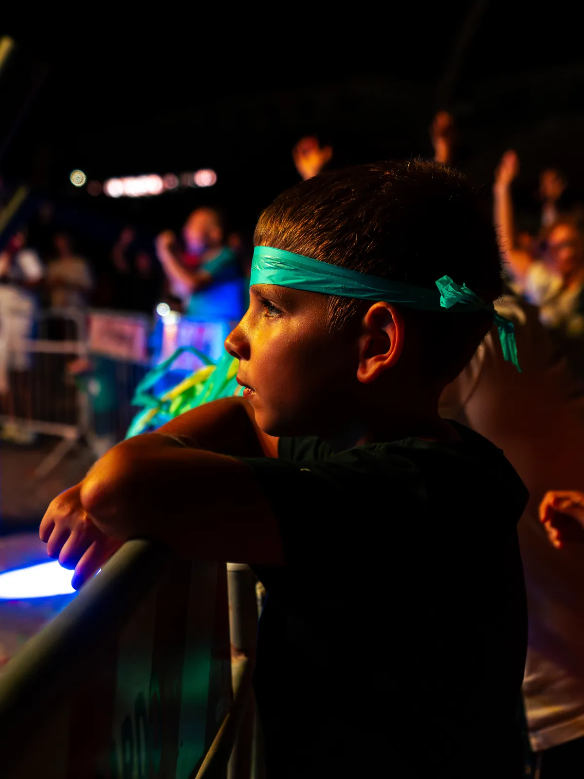 Bambino con la fascia verde alla transenna guarda il palco del Festival in Piazza
