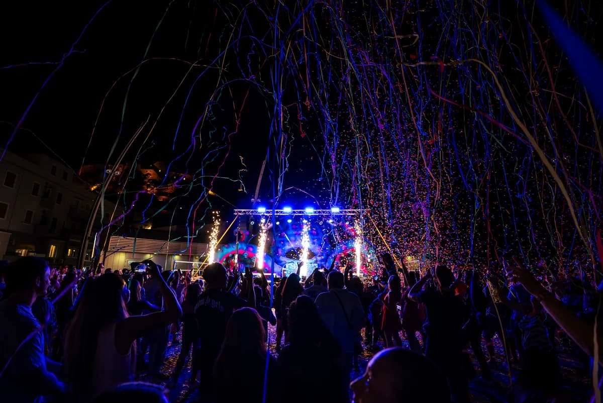 Il palco del Festival in Piazza di notte, tra fasci di luce, fiamme e coriandoli sulla folla