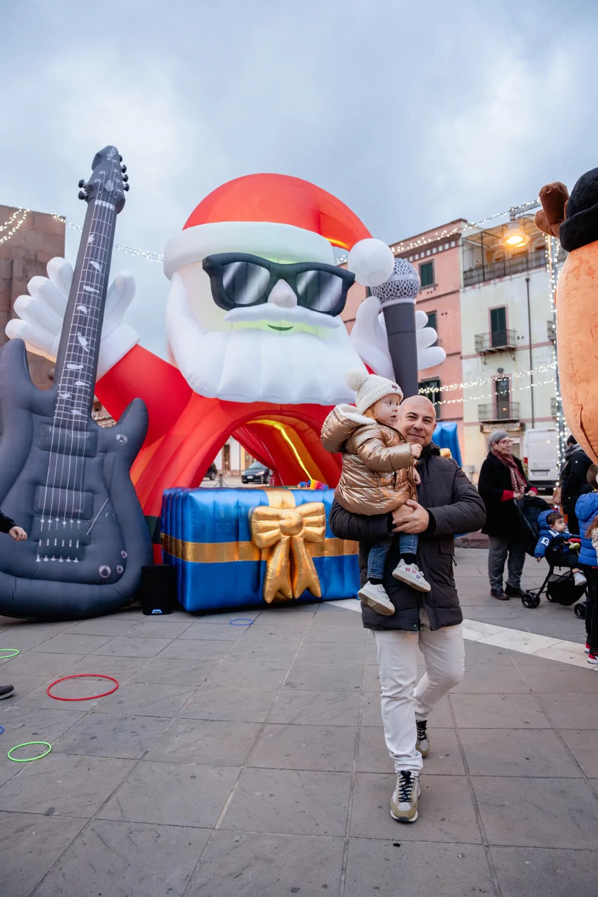 Il Babbo Natale rockstar gonfiabile con microfono e chitarra elettrica gigante in piazza