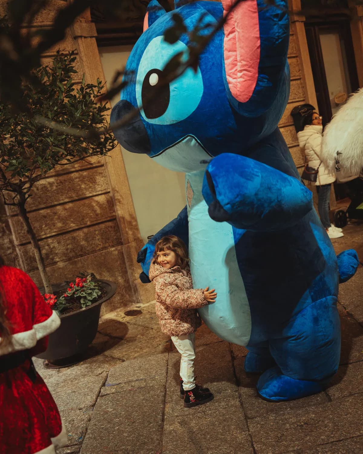 Bambina abbraccia la mascotte gigante di Stitch al Villaggio di Natale