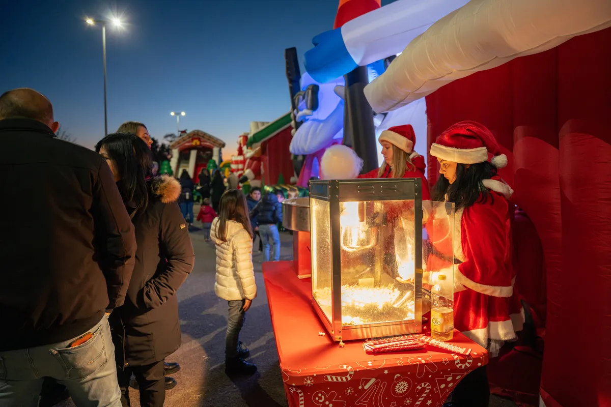 Lo staff in costume da Babbo Natale prepara i popcorn alla casetta delle leccornie illuminata