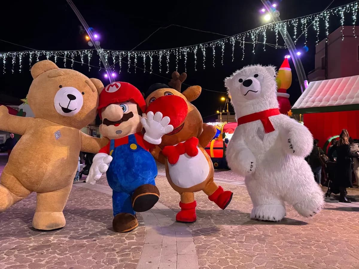 Le mascotte del Villaggio di Natale in gruppo sotto le luminarie: orso Teddy, Super Mario, la renna e l'orso polare