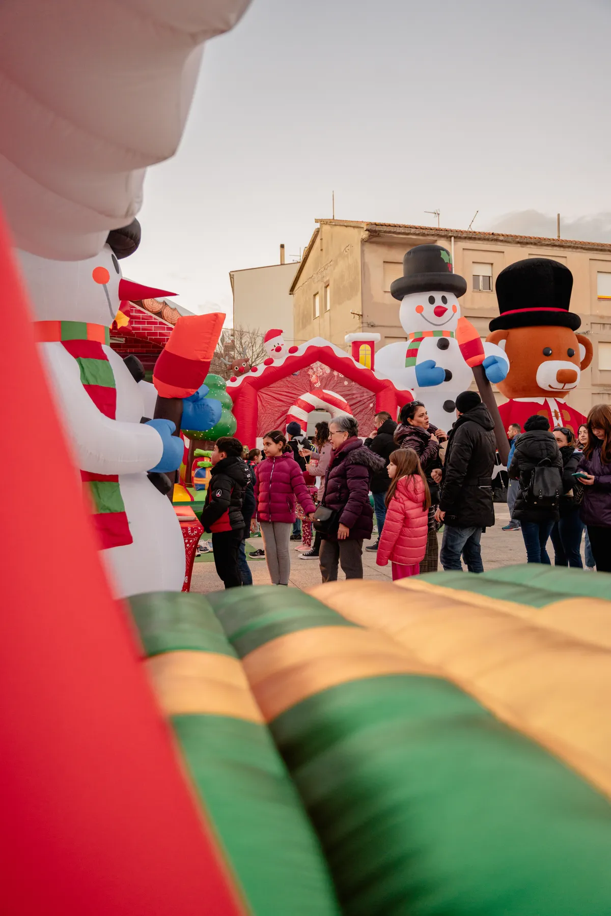 Pupazzi di neve giganti col cilindro e orso di Natale tra la gente in piazza