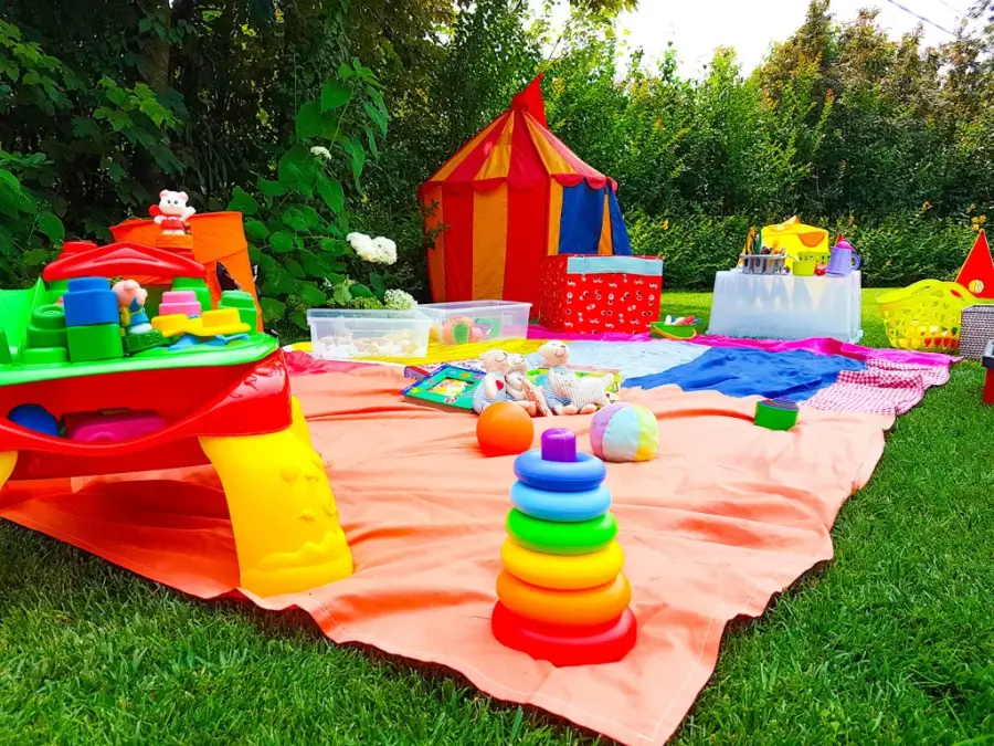 Area bimbi allestita sul prato con tenda, giochi e tappeti colorati