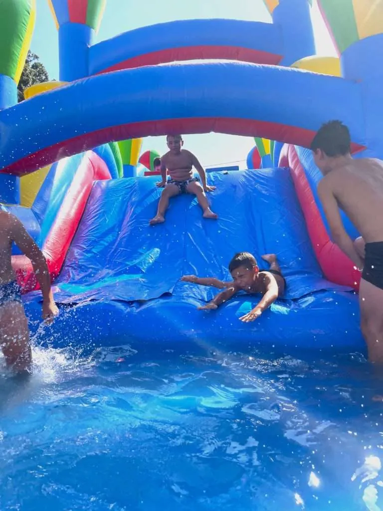 Bambini che scendono da uno scivolo gonfiabile ad acqua in una piscina
