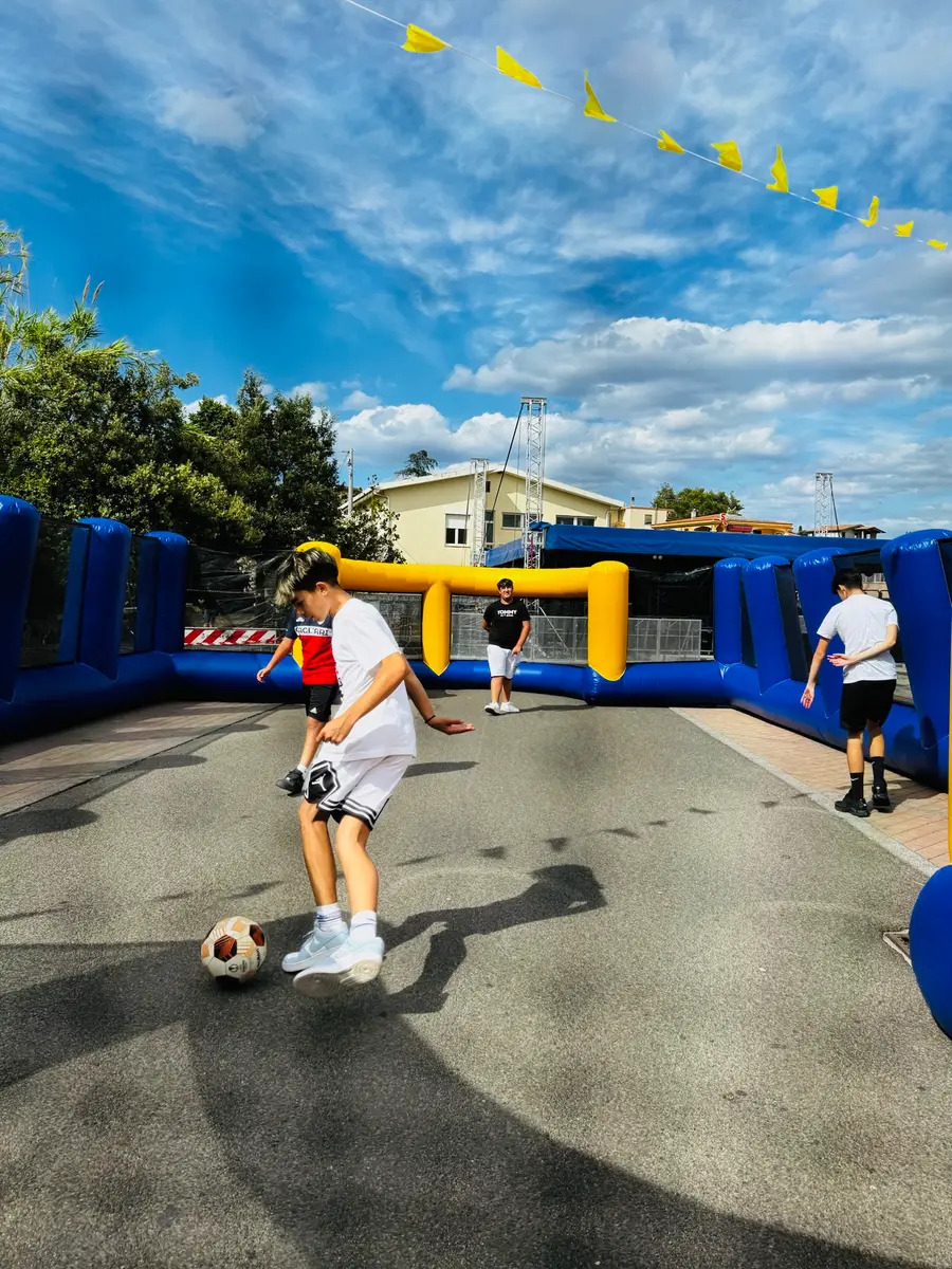 Ragazzo con il pallone dentro l'arena calcio gonfiabile blu e gialla