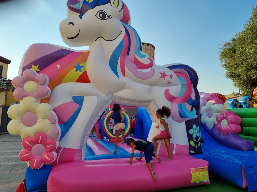 Bambini che giocano su un castello gonfiabile a forma di unicorno con scivolo