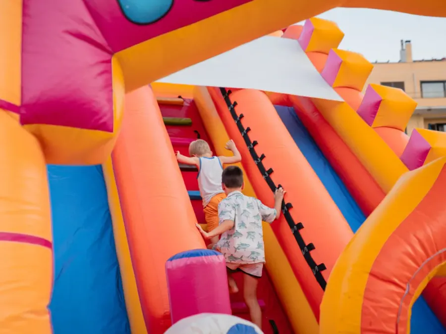 Due bambini salgono la rampa di uno scivolo gonfiabile gigante