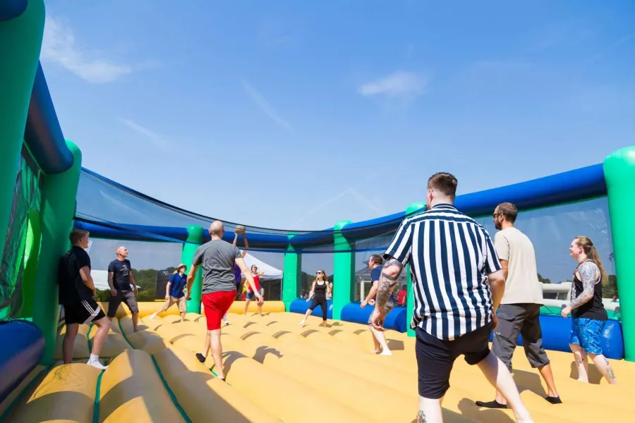 Gruppo di adulti gioca a pallavolo su un grande campo gonfiabile all'aperto