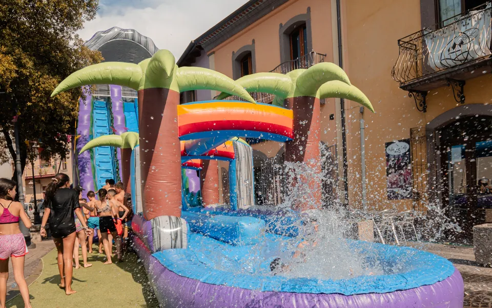 Scivolo gonfiabile ad acqua con palme in una piazza di paese