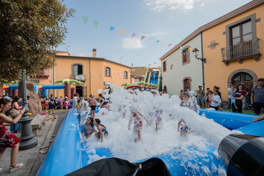 Bambini che giocano nella schiuma dentro la vasca gonfiabile, in piazza