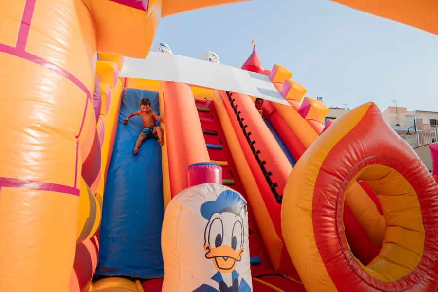 Bambini che giocano su un grande castello gonfiabile con scivoli, in piazza d'estate