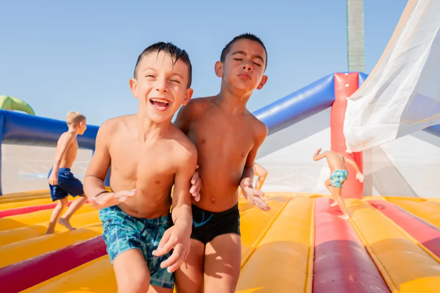 Due bambini che scendono ridendo dallo scivolo gonfiabile