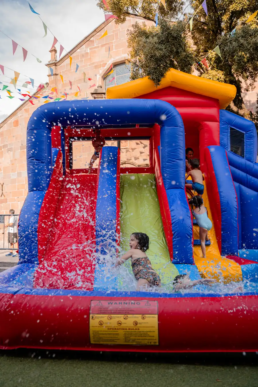 Bambino che scende nello scivolo gonfiabile ad acqua tra gli spruzzi