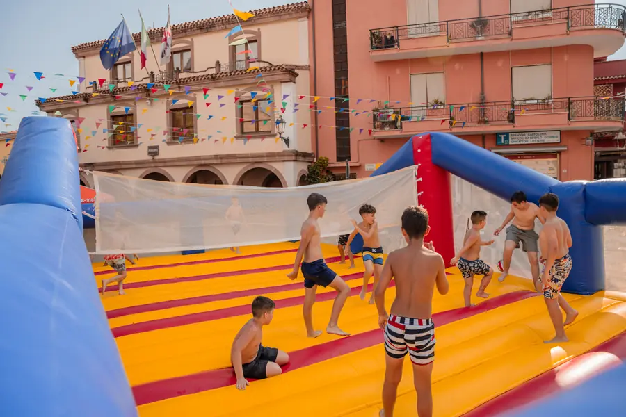 Ragazzi che giocano a pallavolo su un grande campo gonfiabile in piazza