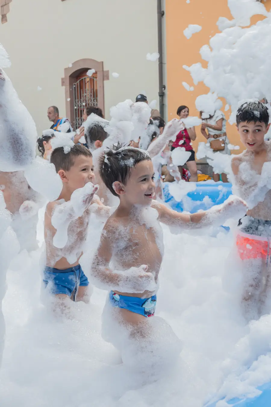 Bambini che giocano dentro la schiuma durante uno schiuma party