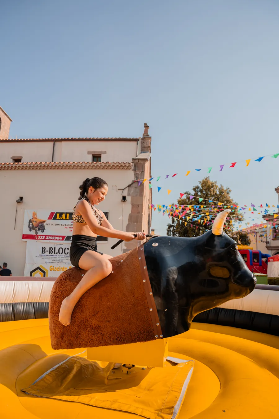 Bambina in equilibrio sul toro meccanico gonfiabile, in piazza